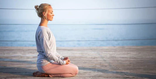 Kobieta medytująca na molo.